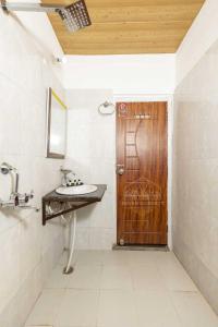 a bathroom with a sink and a wooden door at Hotel O Amantran View in Muzaffarnagar