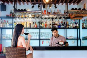 Een man die een vrouw een glas wijn schenkt in een bar. bij Dylan Hotel Danang in Da Nang