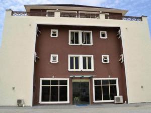 a large brown and white building with windows at Ellyxville Hotel in Lekki