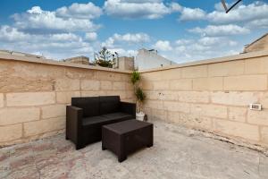 a black couch and stool on a brick wall at Vittoria Luxury House in Lecce