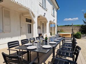 uma longa mesa com copos de vinho e cadeiras num pátio em Le Nid du Chardonnay 
