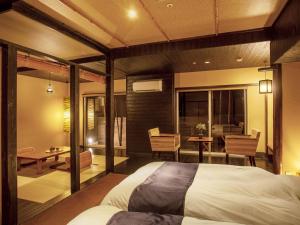 a bedroom with a bed and a table and chairs at Yukai Resort Premium Miyoshiya in Shinonsen