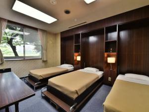 a room with two beds and a table and a desk at Hotel Kangetsuso in Tokyo