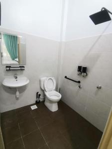 Un baño con un inodoro blanco y un lavabo. en Rasyid Aideen Homestay, en Kijal