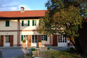 a large house with green windows and a tree at Tenuta Montanello B&B in Castiglione Falletto