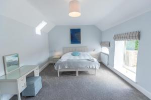 a white bedroom with a bed and a desk at Butterwick - Barn Conversion with a hot tub on a Country Estate in Holbeck