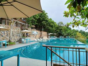 a large swimming pool with chairs and an umbrella at Mist Mountain Resort powered by Cocotel in Cebu City