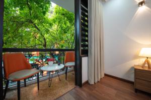 um quarto com uma varanda com uma mesa e cadeiras em Hanoi Liliane Hotel and Travel em Hanói
