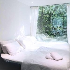 1 cama con sábanas y almohadas blancas frente a una ventana en Time Capsule Retreat, Sungai Lembing, en Sungai Lembing