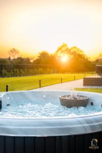 eine Whirlpool-Badewanne mit Sonnenuntergang im Hintergrund in der Unterkunft Sunset House & Spa in Ustrzyki Dolne