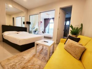 a bedroom with a bed and a yellow couch at The Shore Kota Kinabalu City Centre by LW Suites in Kota Kinabalu