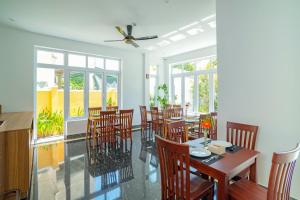 a dining room with a table and chairs and windows at White House Central Villa in Hoi An