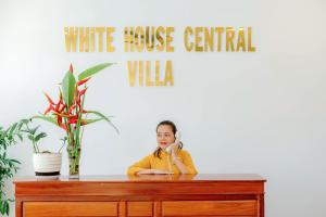Uma rapariga sentada numa secretária a falar ao telefone. em White House Central Villa em Hoi An