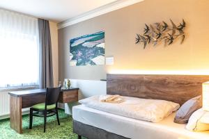 ein Schlafzimmer mit einem Bett, einem Schreibtisch und einem Stuhl in der Unterkunft Pension Schwalbennest in Bösleben-Wüllersleben