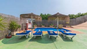 a patio with chairs and a pool with a table and umbrellas at Villa Mariposas Torrox by Ruralidays in Torrox