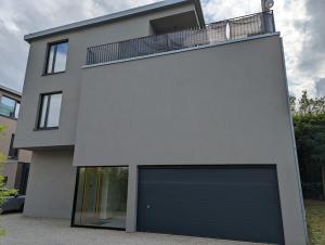 una casa blanca con una puerta de garaje negra en Stylish 2BR Apartment w/ Garage+Garden in Howald/Hesperange, en Hesperange
