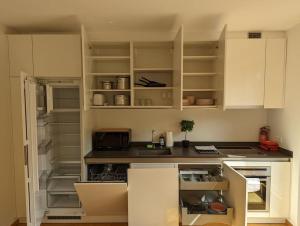 cocina con armarios blancos y nevera abierta en Stylish 2BR Apartment w/ Garage+Garden in Howald/Hesperange, en Hesperange