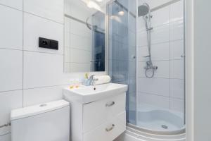 a white bathroom with a sink and a shower at Modern Studio Radomska by Renters in Krakow