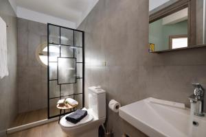 a bathroom with a toilet and a sink and a mirror at Cathedral Suites in Heraklio