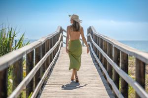a woman walking down a wooden bridge near the beach at Hotel Playas de Guardamar in Guardamar del Segura