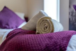 a purple blanket sitting on top of a bed with pillows at Modern & Classy 2 bedroom flat, Free Parking 