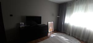 een slaapkamer met een bed, een tv en een raam bij Aпартамент за гости Mари in Kyustendil
