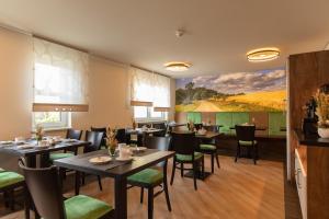 ein Restaurant mit Tischen und Stühlen und einem Gemälde an der Wand in der Unterkunft Pension Schwalbennest in Bösleben-Wüllersleben