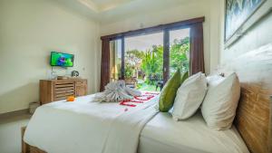 ein Schlafzimmer mit einem weißen Bett mit Kissen und einem Fenster in der Unterkunft Jegeg Mas in Ubud