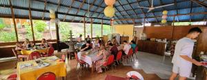a group of people sitting at tables in a restaurant at Bunaken Villa Queen's Dive in Bunaken