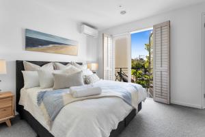 a white bedroom with a large bed and a balcony at Bev's Retreat by Ready Set Stay in Melbourne
