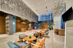 a lobby with tables and chairs in a building at UrCove Hangzhou North Grand Canal in Hangzhou