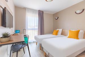 a hotel room with two beds and a desk at Appart'City Classic Arlon - Porte du Luxembourg in Arlon