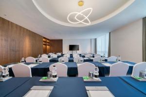 uma sala de conferências com mesas azuis e cadeiras brancas em UrCove Hangzhou North Grand Canal em Hangzhou