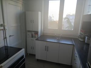 a kitchen with white cabinets and a large window at Appartement cosy 6 personnes proche gare in Rueil-Malmaison