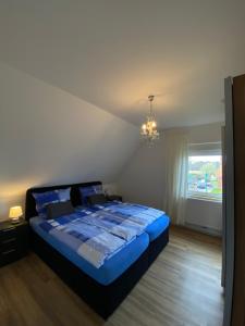 a bedroom with a bed with blue sheets and a chandelier at Refugium in Nortrup in Nortrup