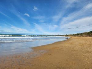 a beach with a person walking on the sand at Beachbach16 - Kakanui in Kakanui