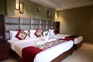 two beds in a hotel room with a large headboard at De Alturas Resort in Candolim