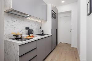 a kitchen with white cabinets and a marble wall at Area1 Center Luxury Apartment with sauna in Rijeka