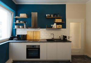 una cocina con armarios blancos y una pared azul en Huge apartment with Sauna and free parking, en Duisburg