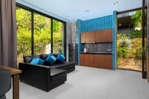 a living room with a black couch and blue pillows at Romantic villa in the tropics near Kamala Beach in Kamala Beach