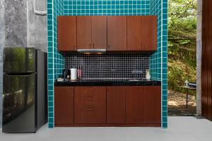 a kitchen with brown cabinets and a blue tile wall at Romantic villa in the tropics near Kamala Beach in Kamala Beach