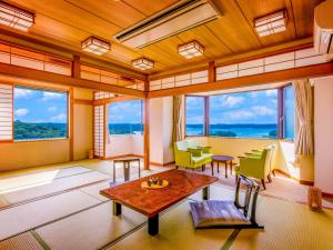 een woonkamer met ramen en een tafel en stoelen bij Yukai Resort Premium Shima Saichoraku in Shima