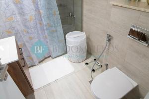 La salle de bains est pourvue de toilettes et d'un rideau de douche. dans l'établissement Stylish 1 Bedroom In Oasis, à Al Qurayyah