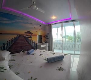 una camera da letto con un letto e un dipinto di un molo di Wind Breeze Sunset View Inn a Guraidhoo