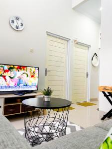 a living room with a table and a flat screen tv at Homestay Kamar Tamu Sedayu in Bantul