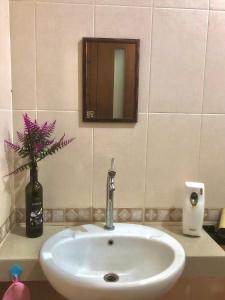 lavabo con espejo y jarrón con flores en Villa Sentul Onnelik Sentul City Bogor by Villaloka, en Babakan Madang