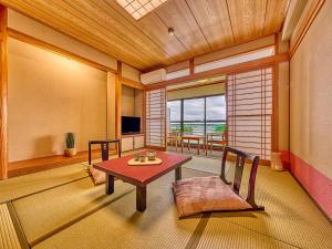 a room with a table and chairs and a television at Yukai Resort Premium Shima Saichoraku in Shima