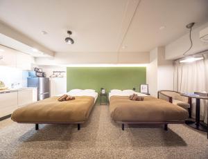 two beds in a room with a green wall at Apartment Hotel 11 Shinsaibashi in Osaka