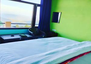 1 dormitorio con cama y pared verde en Corner Inn Homestay - Kausani, en Kausani