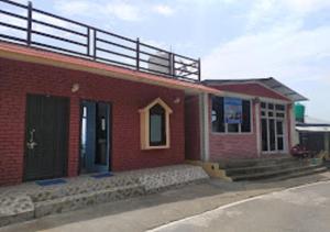 un edificio de ladrillo rojo con balcón en la parte superior en Corner Inn Homestay - Kausani, en Kausani